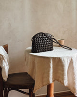 Bembien Carmen Bag in Black on a linen-covered café table beside a coffee cup