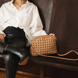 Bembien Carmen Bag in Caramel placed on a couch alongside a seated woman