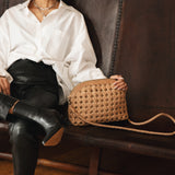 Bembien Carmen Bag in Caramel placed on a couch alongside a seated woman