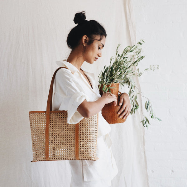 Bembien Margot Bag in Medium Caramel Rattan on the shoulder of a woman holding a plant