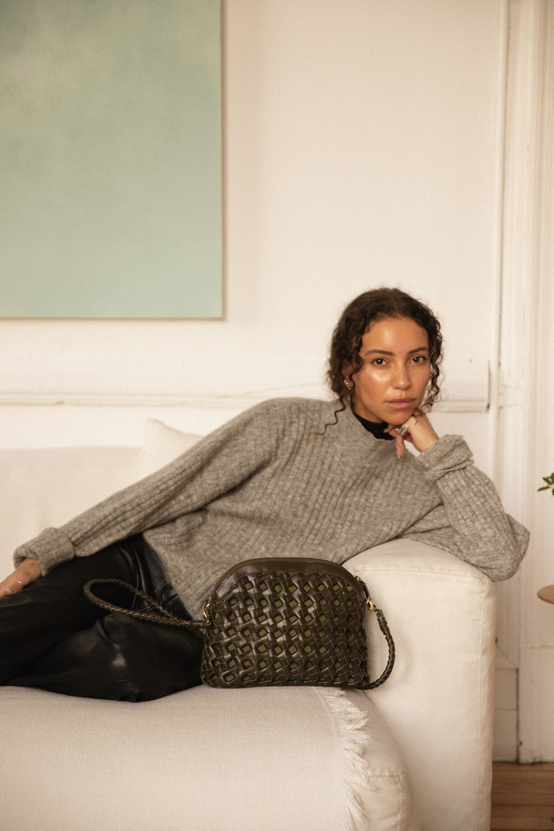 Woman sitting on couch next to Bembien Carmen bag in Olive
