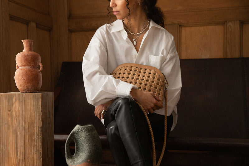 Woman sitting next to ceramics holding Bembien Carmen Bag in Caramel