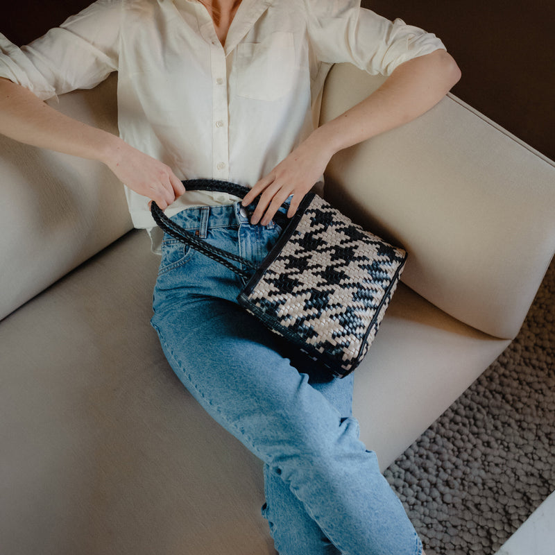 Bembien Ella Bag in White/Black Houndstooth placed in the lap of a seated woman