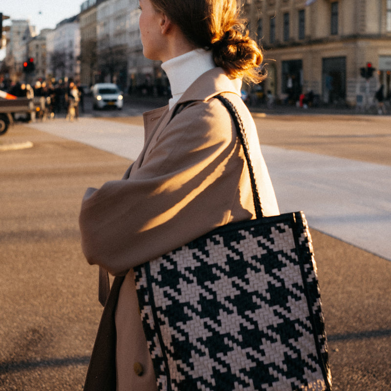 Bembien Le Tote in white/black houndstooth on the shoulder of a woman walking in a city