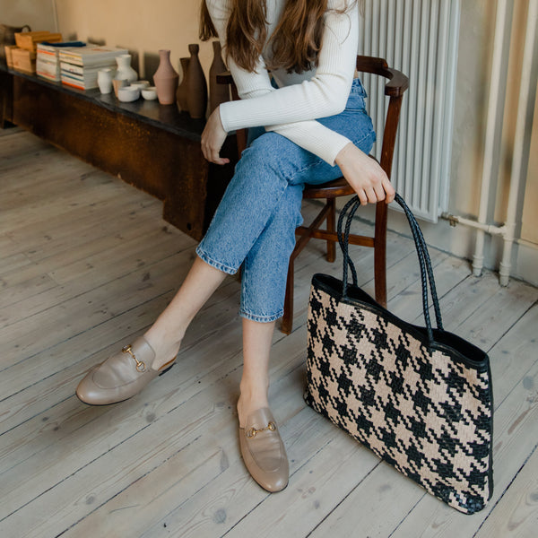 Bembien Gabrielle Bag in Caramel/Black Houndstooth placed on the floor and held by a seated woman