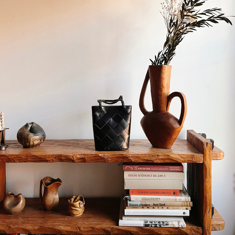 Bembien Bonita Bag Grande Weave in Black placed on a shelf alongside plants and books