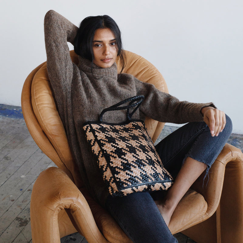 Bembien Le Tote in Caramel/Black Houndstooth placed in the lap of a seated woman