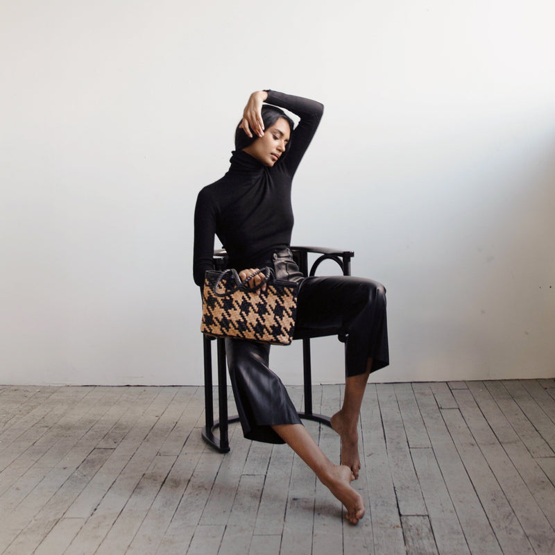 Bembien Ella Bag in Caramel/Black Houndstooth placed in the lap of a seated woman