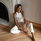 Bembien Lucia Bag in Rattan in the lap of a seated woman